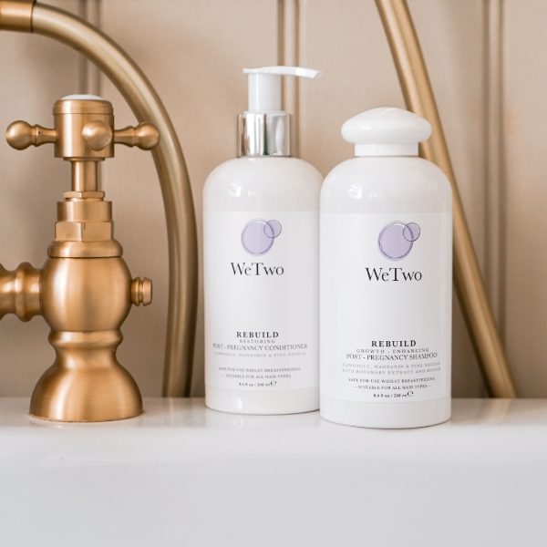 Two bottles of WeTwo Rebuild product on a bathroom counter with a gold faucet in the background.